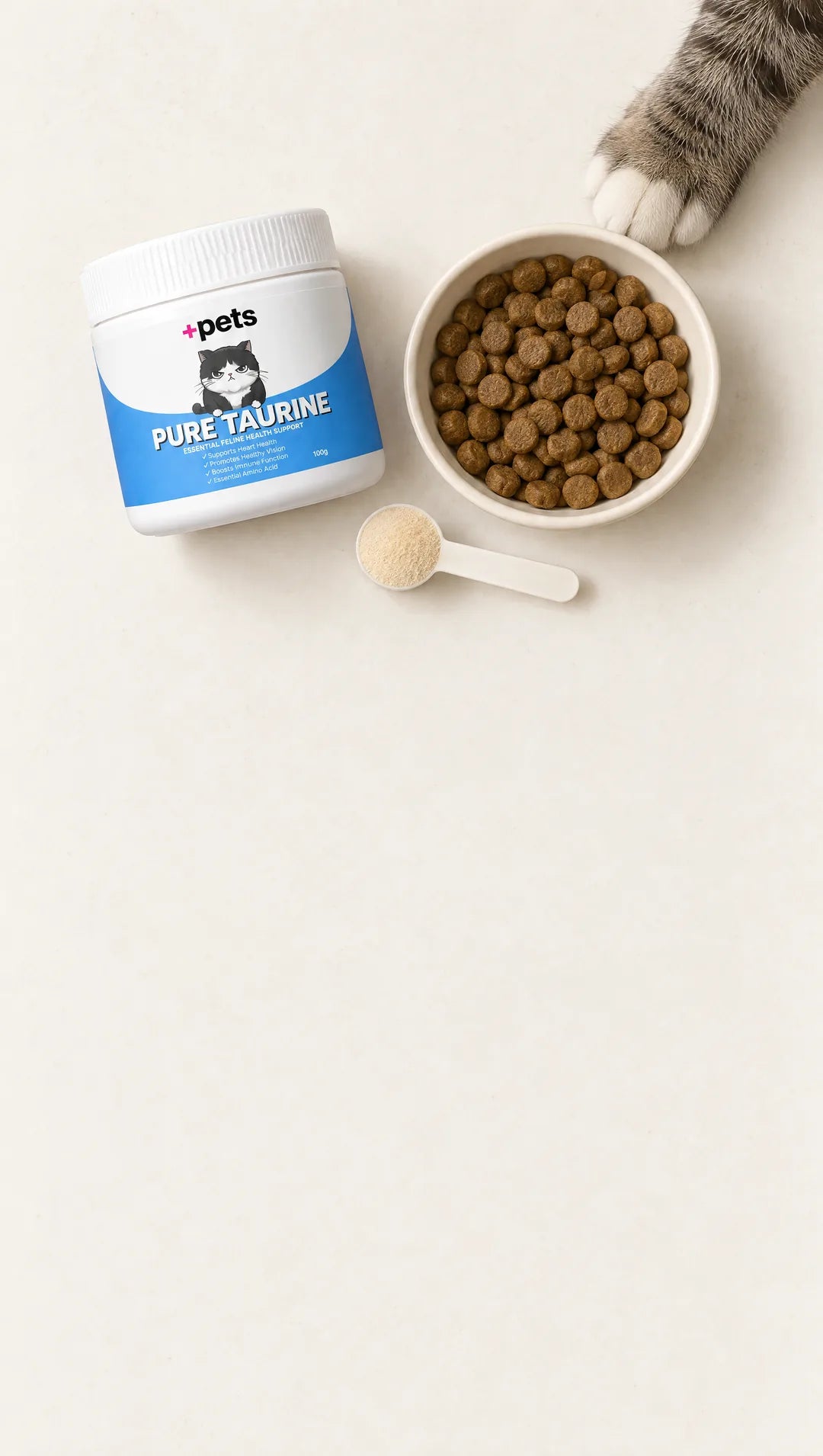 Overhead view of a +Pets Pure Taurine jar, a bowl of dry food and a scoop of powder, a tabby paw reaching in from the top